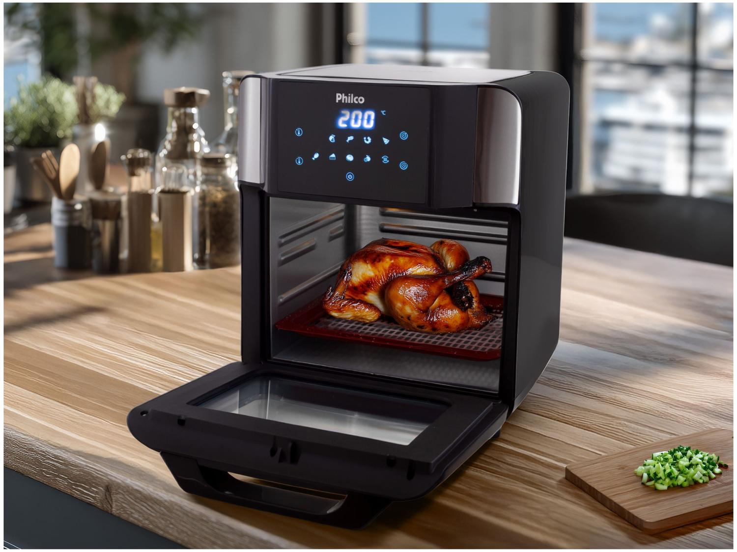 Air Fryer Philco 15L sobre bancada de madeira com um frango assado dentro