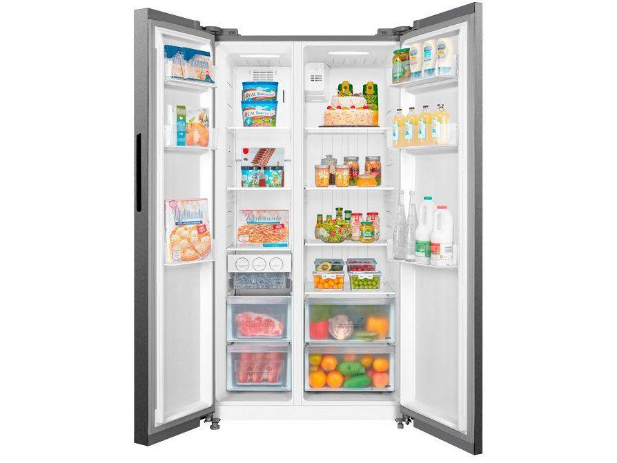 Geladeira Midea Side by Side aberta e totalmente abastecida com alimentos, frutas e bebidas organizados.
