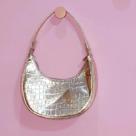 Bolsa feminina dourada em formato meia lua.
