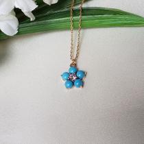 Colar dourado com pingente flor em resina azul clara e miolo em zircônia rosa. Colar dourado com pingente flor em resina azul clara e miolo em zircônia rosa.