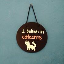 Plaquinha decorativa com cordinha "I believe in catcorns " - geek brazilian