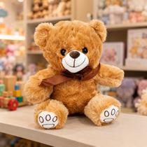 Urso de Pelúcia Toninho com Laço 25cms Cor:Marrom Claro Urso de Pelúcia Toninho com Laço 25cms Cor:Marrom Claro