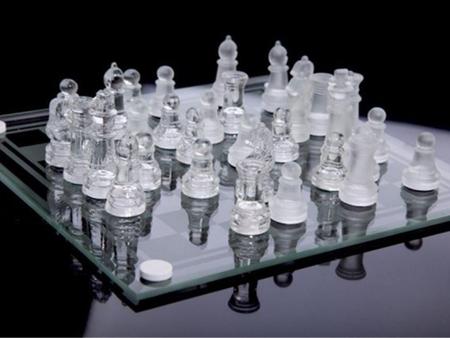 Peças de xadrez de vidro em um tabuleiro de xadrez de vidro com reflexão.