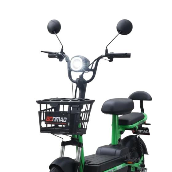 Detalhe do guidão e farol aceso de bicicleta elétrica verde com cesto e assento duplo