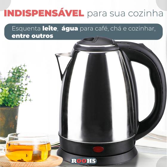 Chaleira elétrica de inox sobre uma mesa de madeira ao lado de uma xícara de chá e uma planta decorativa