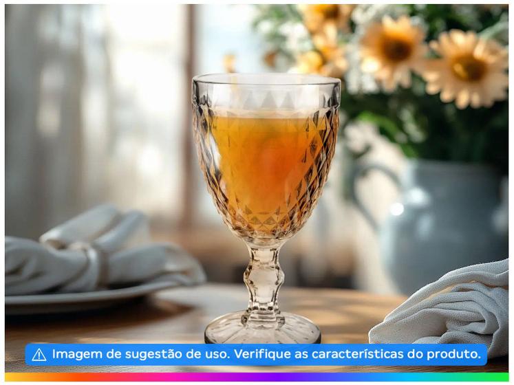 Taça de vidro Bico de Jaca preenchida com suco em uma mesa posta com guardanapos de tecido e flores ao fundo