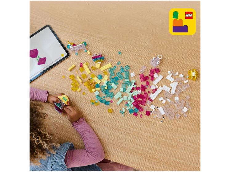 Criança montando peças translúcidas do LEGO Classic 11040 sobre uma mesa com auxílio de um tablet
