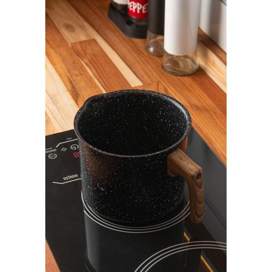 Leiteira de indução Wolff preta com cabo amadeirado sobre um fogão de indução