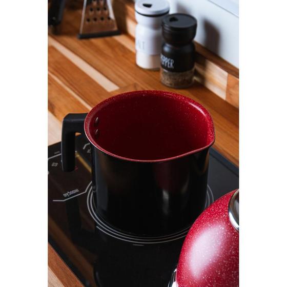 Leiteira Lyor em cima de um cooktop de indução ao lado de utensílios de cozinha