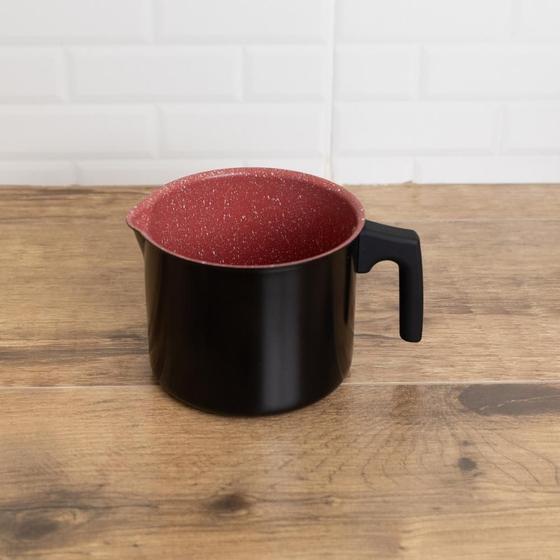 Leiteira Lyor de 1,7L com exterior preto e interior vermelho em superfície de madeira